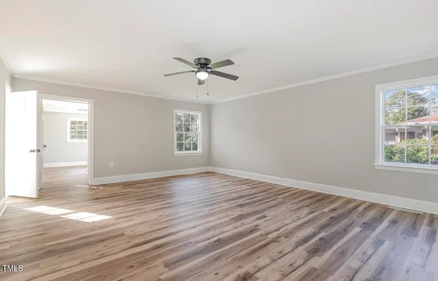 a view of empty room with wooden floor and fan