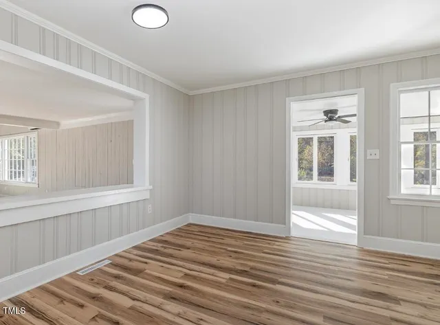 a view of an empty room with wooden floor and a window