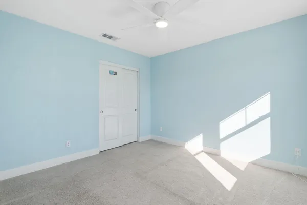 an empty room with a window and a ceiling fan