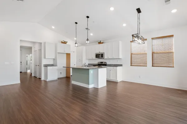a view of kitchen with stainless steel appliances kitchen island wooden floors and white cabinets