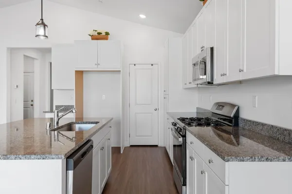 a kitchen with granite countertop a sink a stove and refrigerator