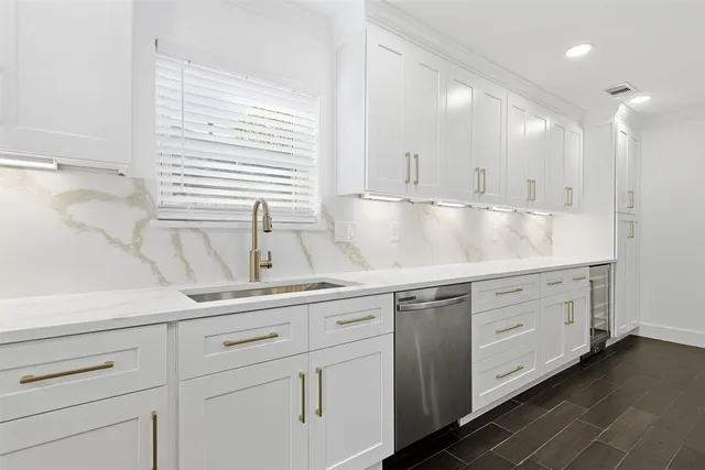 a view with cabinets a sink and dishwasher a stove with wooden floor