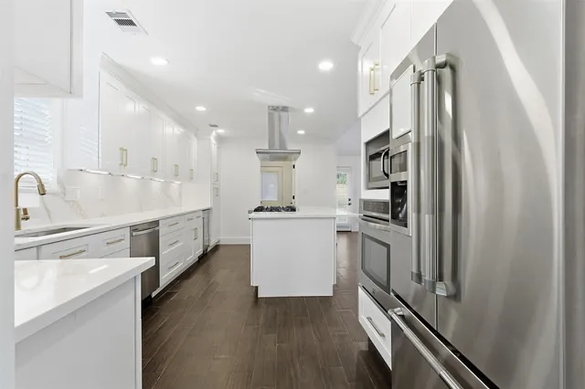 a kitchen with stainless steel appliances white cabinets and wooden floors