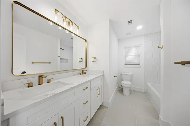 a bathroom with a double vanity sink toilet mirror and vanity