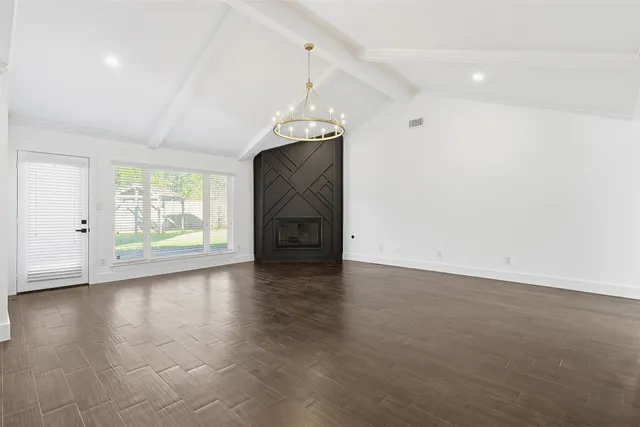 an empty room with wooden floor cabinet and windows