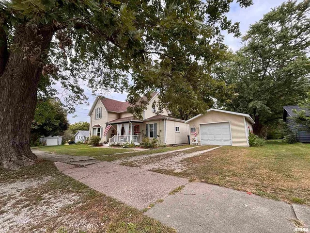 a front view of a house with a yard and large trees