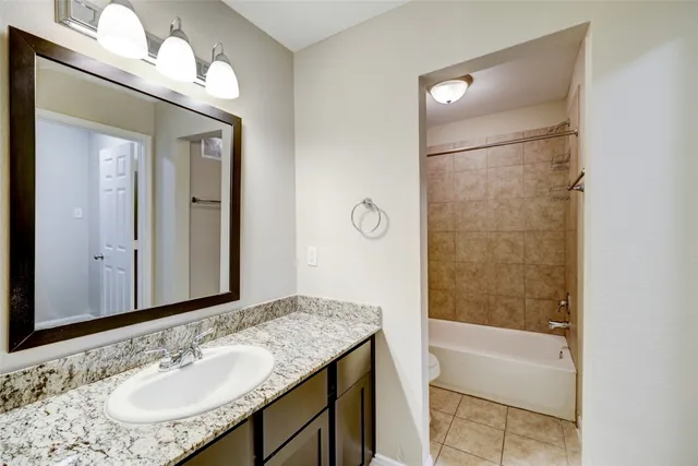 a bathroom with a granite countertop sink mirror and a bathtub