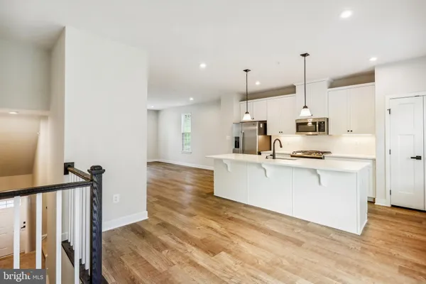 a large white kitchen with white cabinets and wooden floor