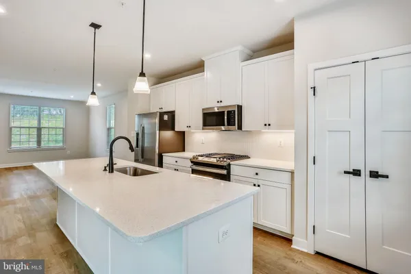 a kitchen with stainless steel appliances a stove a sink a refrigerator a center island and wooden floor