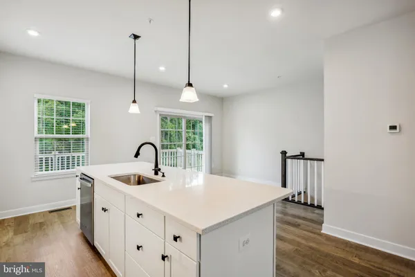 a kitchen with stainless steel appliances granite countertop a sink a oven a dining table and chairs with wooden floor