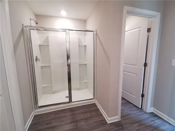 a bathroom with a glass shower door and a wooden floor