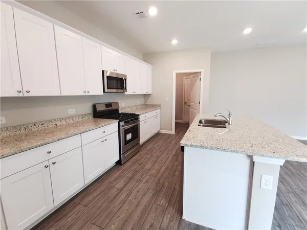 a kitchen with granite countertop white cabinets and white appliances