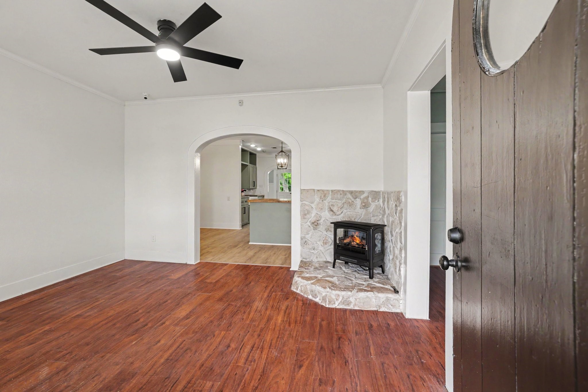 31730 Waller Tomball Road Waller, TX 77484 - Photo 10 of 50 This inviting room features rich vinyl floors, a cozy stone-accented fireplace wall, and an arched entryway leading to a bright kitchen area.
