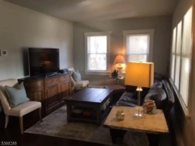 a view of a hallway with wooden floor and a bathroom