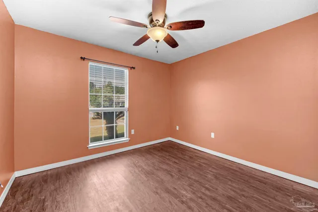 a view of an empty room with window and wooden floor