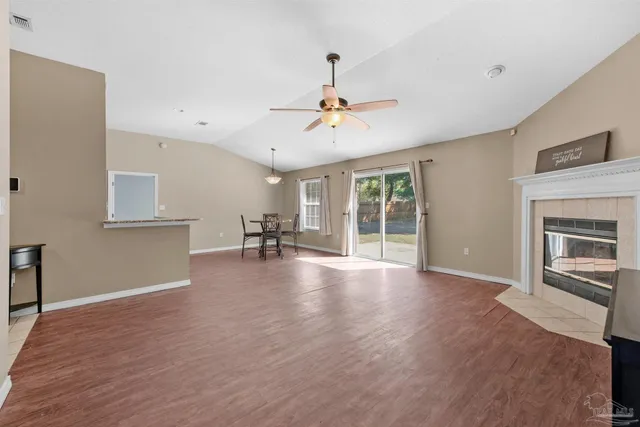 a view of a livingroom with a fireplace a ceiling fan and windows