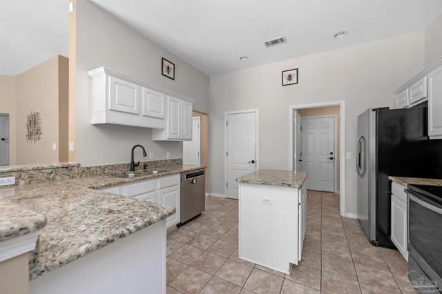 a kitchen with granite countertop a sink stove and refrigerator