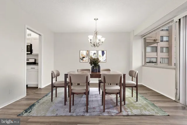 a dining room with wooden floor a chandelier a wooden table and chairs