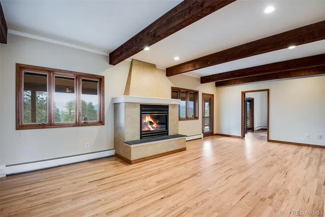 a view of an empty room with wooden floor fireplace and a window