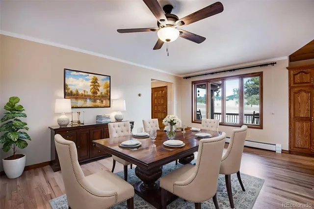 a dining room with wooden floor a chandelier fan a wooden table and chairs