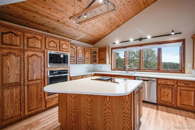 a kitchen with stainless steel appliances granite countertop a sink a stove and a wooden floors