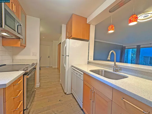 a kitchen with stainless steel appliances granite countertop a sink and a refrigerator