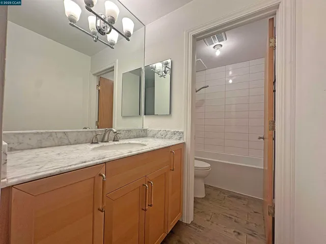 a bathroom with a granite countertop sink a toilet and shower