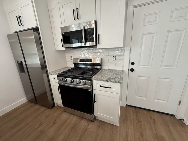 a kitchen with stainless steel appliances a stove a microwave and a hard wood floors