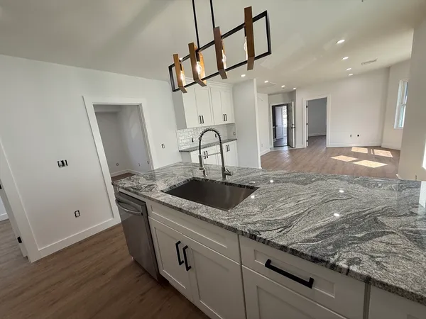 a kitchen with stainless steel appliances granite countertop a sink a stove and cabinets