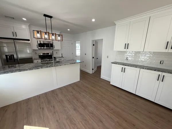 a large kitchen with stainless steel appliances kitchen island a large counter top and a wooden floors