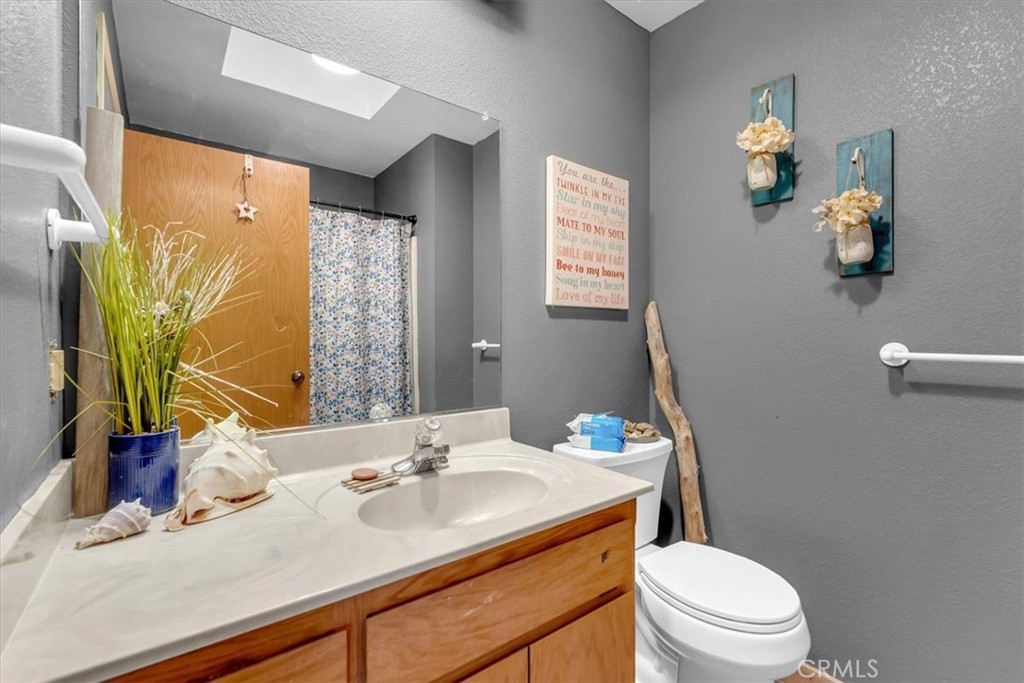 21550 Leaf Avenue Corning, CA 96021 - Photo 25 of 71 a bathroom with a granite countertop sink a toilet and a mirror