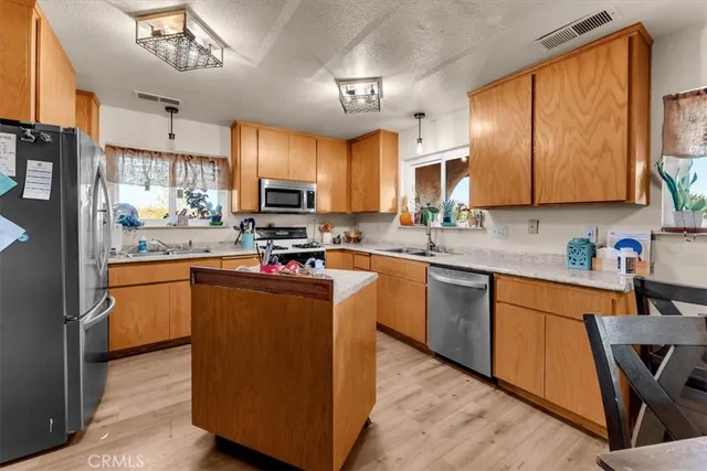 a kitchen with kitchen island granite countertop wooden floors a stove top oven a sink and dishwasher