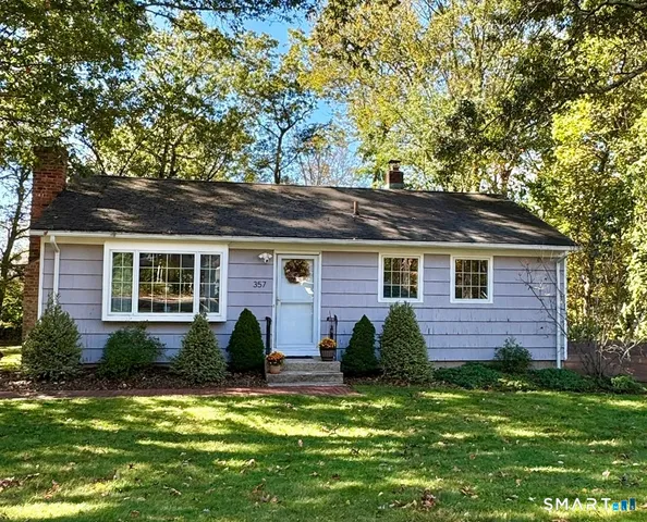 a view of a house with a yard chairs and a large tree