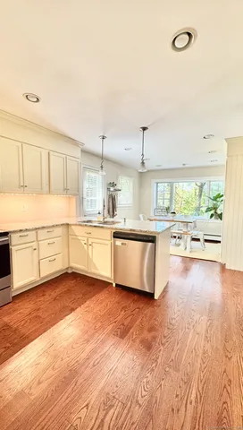 a large kitchen with a stove a sink dishwasher and a refrigerator with wooden floor