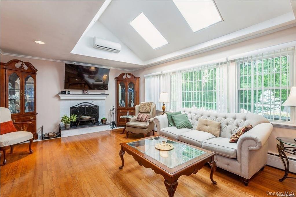 77 Duck Pond Road Glen Cove, NY 11542 - Photo 12 of 36 a living room with furniture a fireplace a flat screen tv and a large window