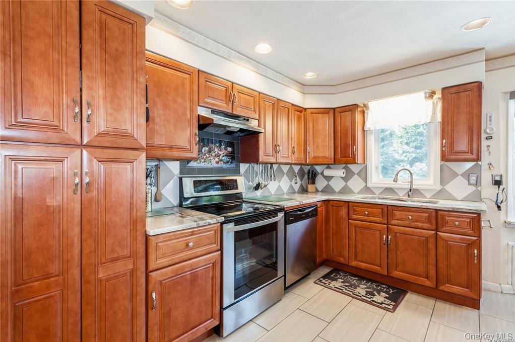 77 Duck Pond Road Glen Cove, NY 11542 - Photo 15 of 36 a kitchen with stainless steel appliances granite countertop a sink a stove a refrigerator cabinets and a window