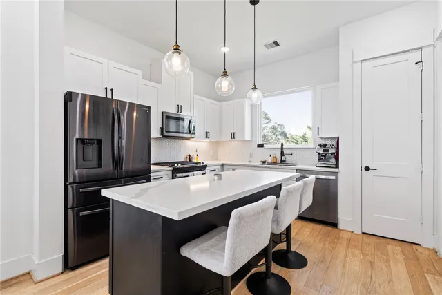 a kitchen with kitchen island a dining table chairs stainless steel appliances and wooden floor