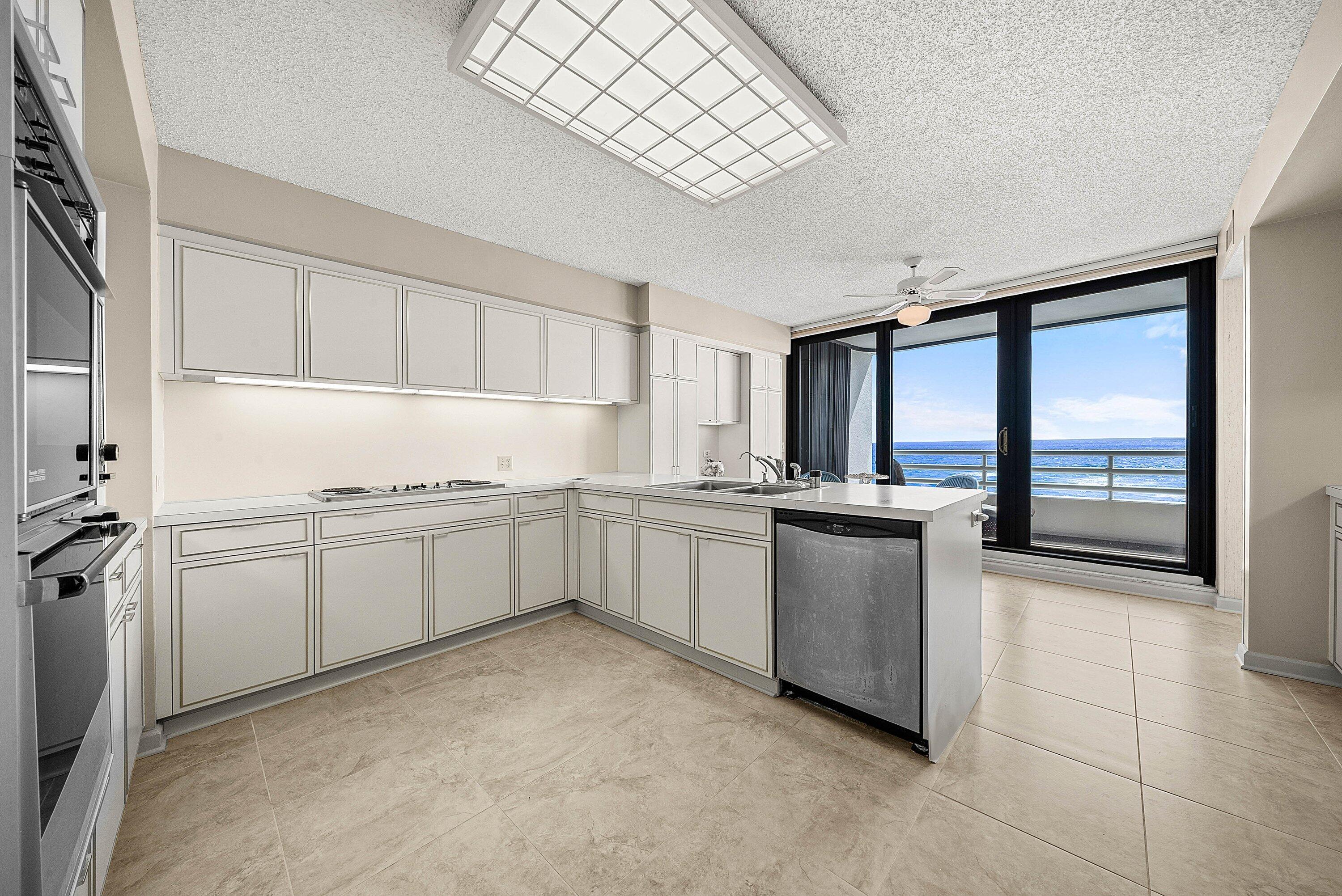 1500 South Ocean Boulevard, Unit 604 Boca Raton, FL 33432 - Photo 21 of 61 a kitchen with a refrigerator and white cabinets