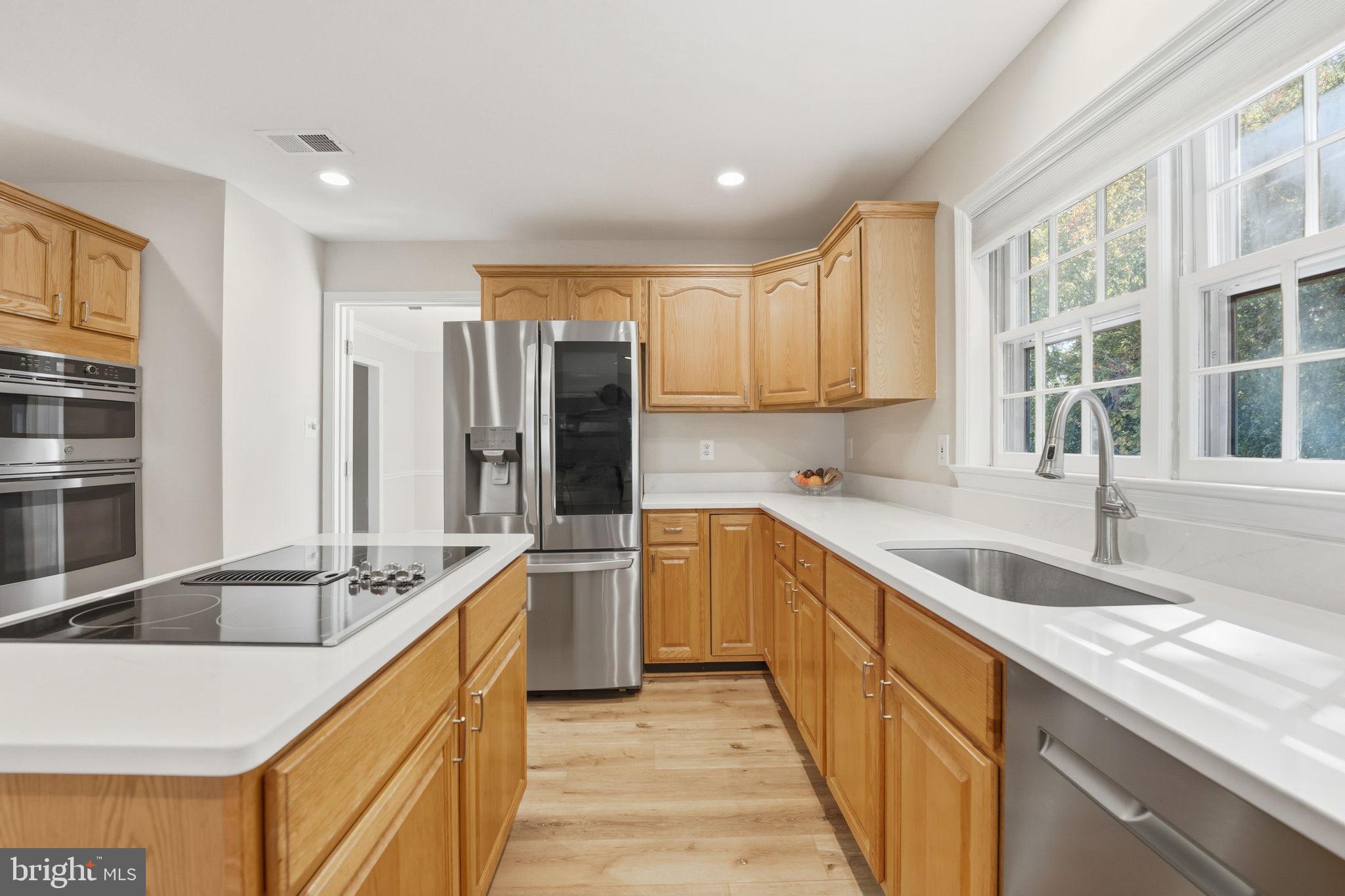 21507 Tithables Circle Broadlands, VA 20148 - Photo 15 of 64 a kitchen with stainless steel appliances granite countertop a sink and dishwasher stove a refrigerator with wooden cabinets