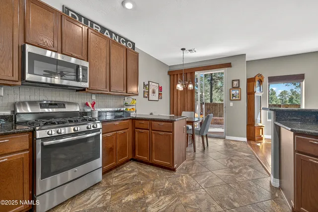 a kitchen with stainless steel appliances granite countertop a stove top oven a sink dishwasher a dining table and chairs with wooden floor