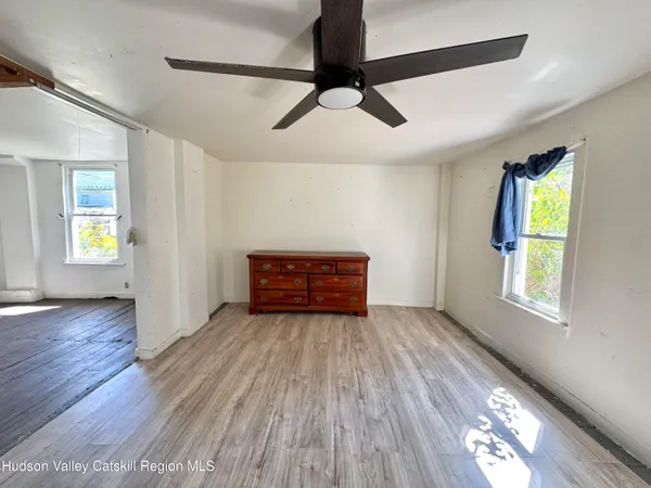 a view of an empty room with wooden floor and a window