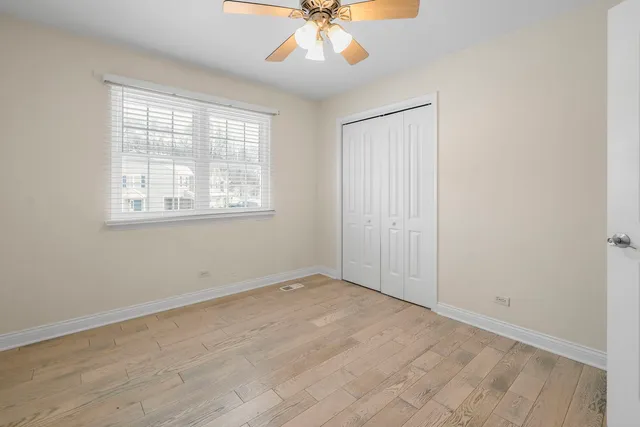 an empty room with a window and a chandelier fan