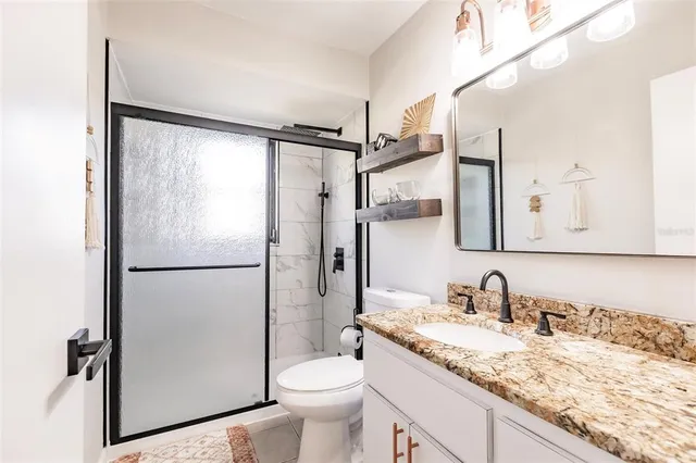 a bathroom with a granite countertop sink toilet and a shower