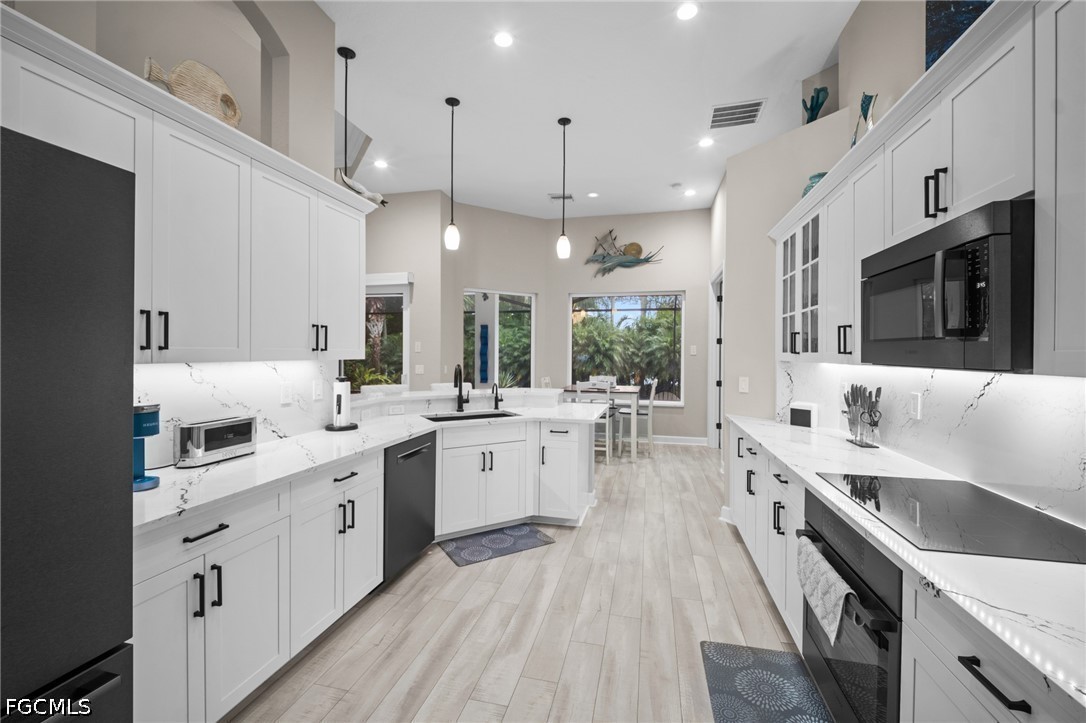 9042 Bronco Court Naples, FL 34113 - Photo 9 of 50 a large white kitchen with a large window a sink stainless steel appliances and cabinets