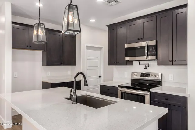 a kitchen with stainless steel appliances a sink a stove a microwave and wooden cabinets