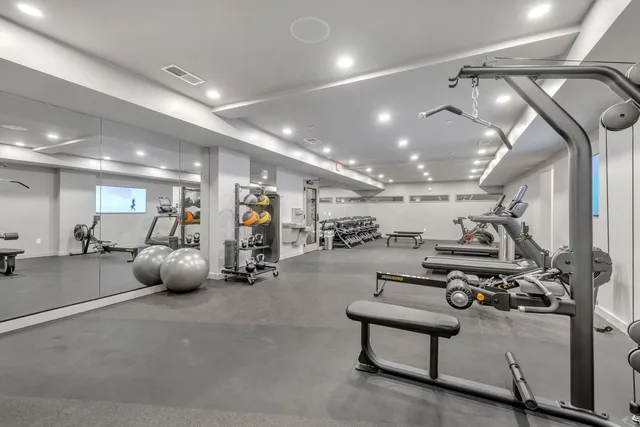 a room with lots of gym equipment and a view of living room