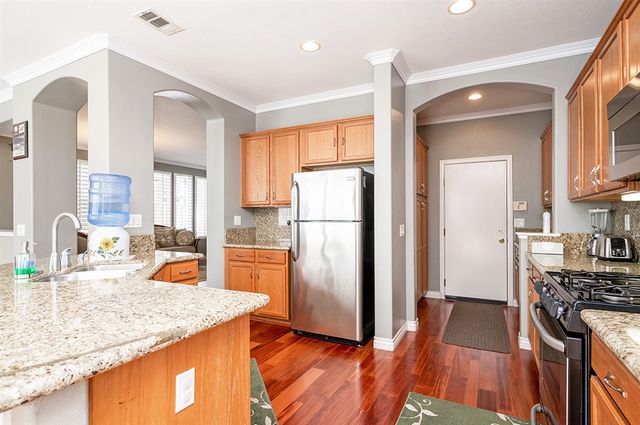 a kitchen with stainless steel appliances granite countertop a refrigerator a stove and a sink with wooden floor