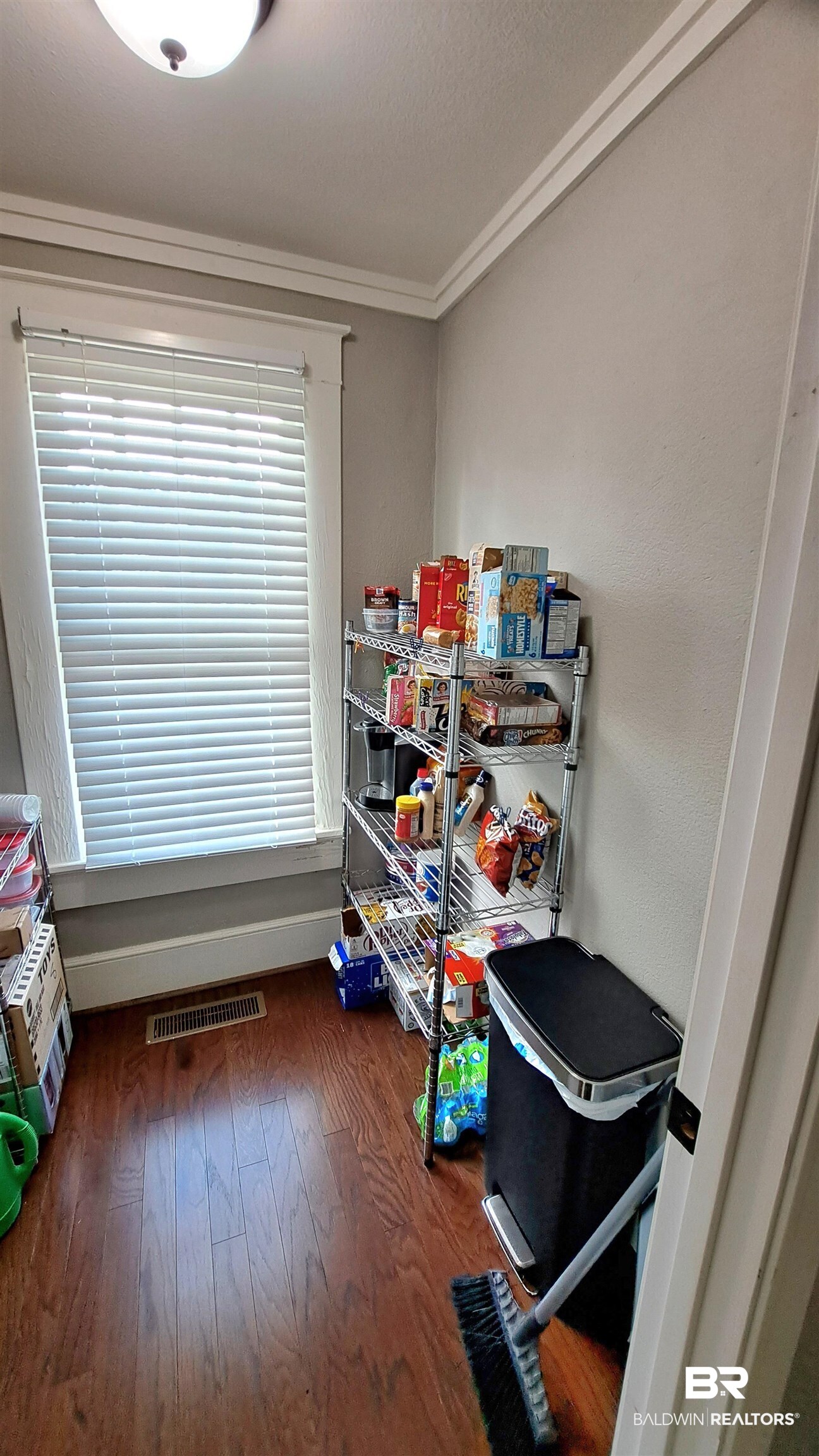 110 South Main Street Evergreen, AL 36401 - Photo 11 of 27 Hardwood-finish flooring and crown molding highlight this functional space, featuring a window with blinds, ceiling-mounted light fixture, and baseboard trim