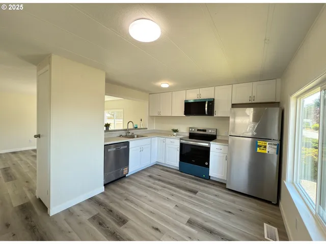 a kitchen with a refrigerator a stove top oven a sink and dishwasher with wooden floor