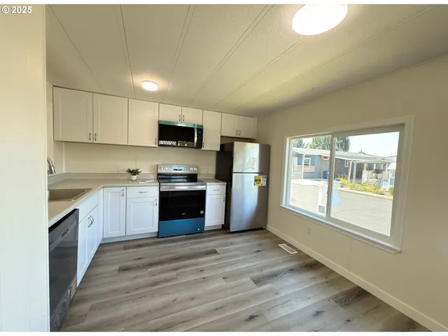 a kitchen with granite countertop a stove top oven a sink dishwasher a refrigerator and a oven with wooden floor